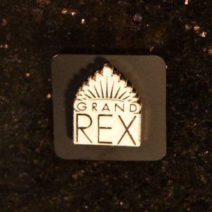 Pin's "Grand Rex" blanc, souvenir dérivé vendu par la boutique du cinéma Le Grand Rex